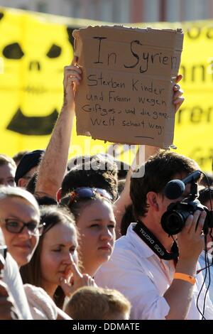 Trier, Germania. 04 Sep, 2013. Una persona che detiene un poster con la scritta "donne e bambini muoiono in Siria a causa di gas tossici e di tutto il mondo guarda l'altro modo' durante un discorso del Cancelliere tedesco Angela Merkel a una campagna elettorale caso del partito cristiano democratico a Treviri, Germania, 04 settembre 2013. Foto: THOMAS FREY/dpa/Alamy Live News Foto Stock