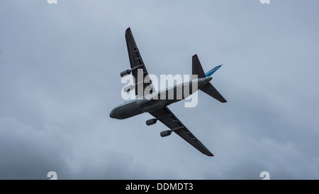 Antonov 124-100-82073 UR jumbo jet transporter cargo aereo underbelly luci di atterraggio su lembi verso il basso cielo molto nuvoloso Foto Stock