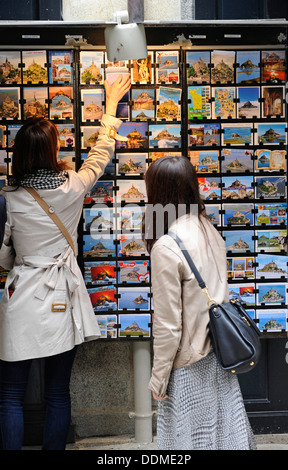 Turista femminile guardando le cartoline al di fuori di un negozio. Foto Stock