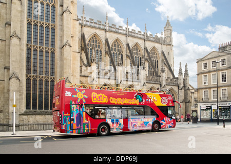 Un red britannico, open top, double decker autobus turistico parcheggiata dall'abbazia nel centro di Bath, Somerset, Regno Unito Foto Stock