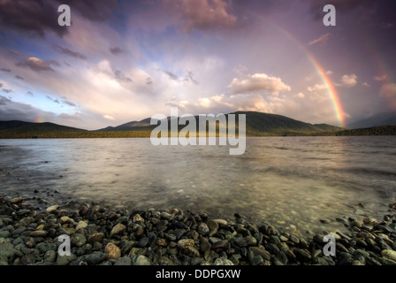 Rainbows oltre Fiordland montagne e Lago Te Anau all'alba. Isola del Sud, Nuova Zelanda Foto Stock