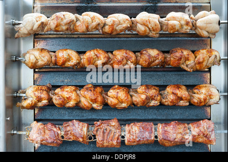 Polli di carne e patate la tostatura su un girarrosto su un mercato francese Bretagna Francia Foto Stock