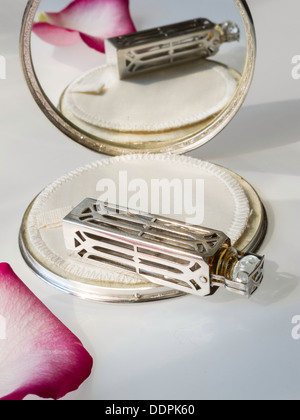 Argento Vintage fiala di profumo si riflette in una polvere compatta per il trucco Foto Stock