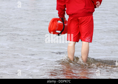 Bagnino di salvataggio con la boa di salvataggio in piedi sul mare di Enniscrone beach, Irlanda Foto Stock