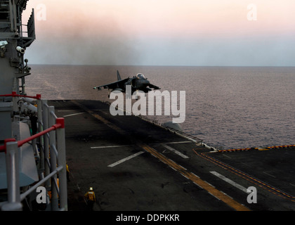 Un AV-8 Harrier da pecora nera di attacco Marino Squadron (VMA) 214 atterra sul ponte di volo di distribuita Amphibious Assault nave USS Bonhomme Richard (LHD 6) al tramonto. Bonhomme Richard è il prodotto di punta della Bonhomme Richard Amphibious pronto Foto Stock