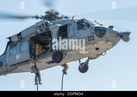 Sailor assegnati per l'eliminazione degli ordigni esplosivi unità mobile (EODMU) 5 fast-corde da un MH-60S Sea Hawk per il ponte di volo di distribuita Amphibious Assault nave USS Bonhomme Richard (LHD 6) durante un esercizio di formazione. Bonhomme Richard è il flagshi Foto Stock