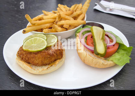 Crabcake Burger faccia aperta con sottaceti cipolla Insalata di pomodoro le fette di limone e patatine fritte Foto Stock