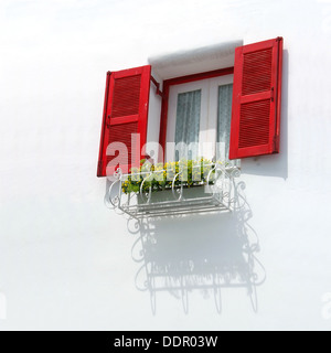 Vintage finestra rossa sul muro bianco e cesto di fiori. Foto Stock