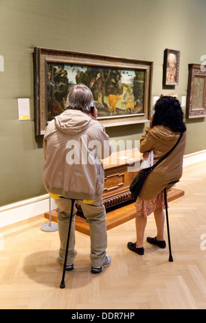 Un giovane seduto su bastoni di tiro apprezzare l'arte dipinti, l'Ashmolean Museum di Oxford Regno Unito Foto Stock