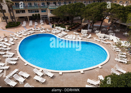 Alta Vista del vuoto hotel piscina circondata da sedie a sdraio vuota. Foto Stock