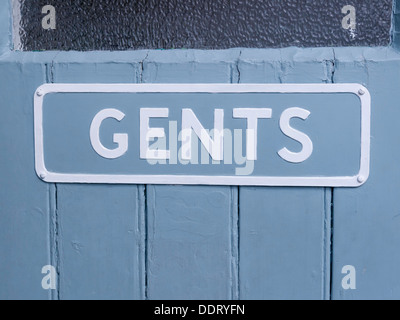 In vecchio stile Gents wc segno ghisa avvitato ad una porta di legno dipinto di grigio e bianco Foto Stock