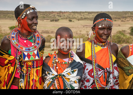 Masai donne che indossano coloratissimi costumi tradizionali, a cantare in un villaggio vicino al Masai Mara, Kenya, Africa Foto Stock