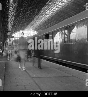 I viaggiatori a piedi lungo una piattaforma a Centraal Station, Amsterdam, Paesi Bassi, 1963. Artista: Michael Walters Foto Stock