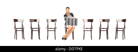 Piuttosto imprenditrice tenendo una valigetta in pelle e in attesa per il colloquio di lavoro su una sedia in legno Foto Stock