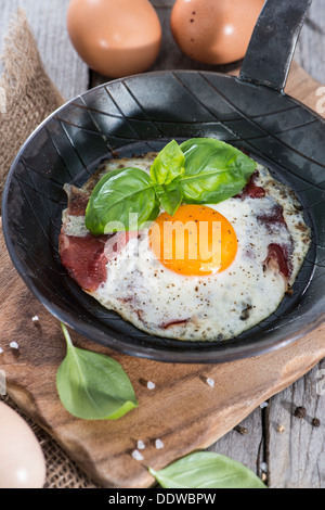 Uovo fritto in una piccola padella su vintage sfondo di legno Foto Stock