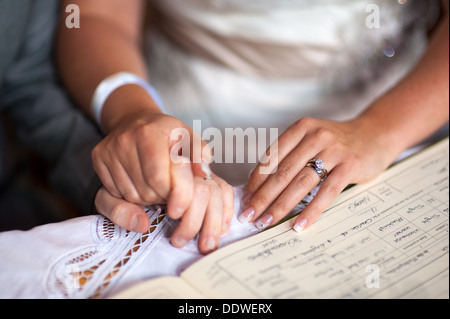 Le mani della sposa e lo sposo a un matrimonio con il matrimonio registrati Foto Stock