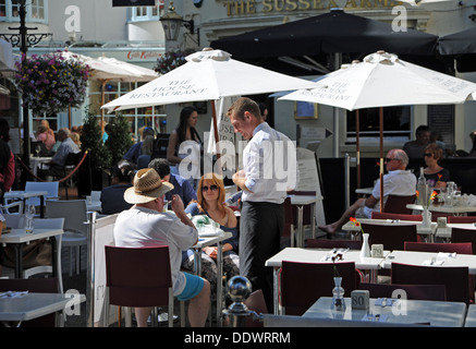 Cameriere che serve i clienti presso il ristorante in stile alfresco al di fuori nelle corsie in area di Brighton Regno Unito Foto Stock