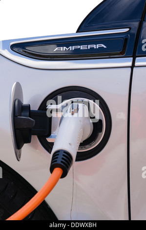 Una Vauxhall Ampera auto elettrica essere ricaricati in corrispondenza di una stazione di carica al parcheggio su strada Parcheggio auto Foto Stock