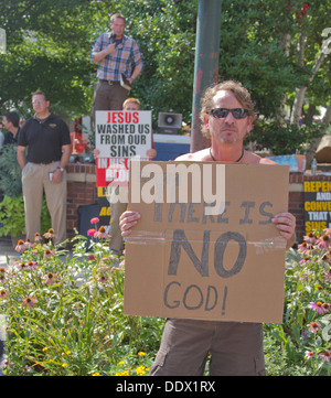 Gli uomini trattenere contrapposte religione e Ateo segni all'Bele Chere Festival in Asheville, North Carolina sulla luglio 26, 2013 Foto Stock