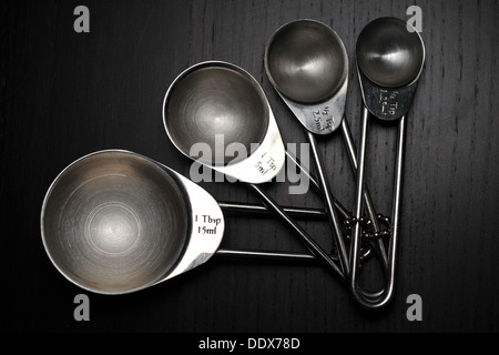 Un set di misurazione cucina cups/cucchiai fotografati contro uno sfondo nero. Foto Stock