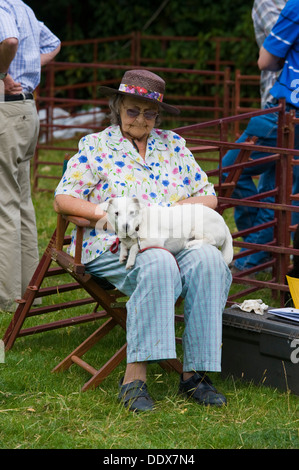 Signora anziana addormentato seduto con il cane sul suo giro al villaggio Cwmdu mostrano Powys Wales UK Foto Stock