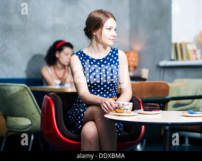 Zoomed donna in abito macchiato sit in cafe Foto Stock