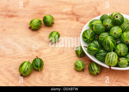 Piatto bianco riempito con piante succulente succosa fresche e mature Ribes verde su un vecchio tavolo di legno alto. Foto Stock