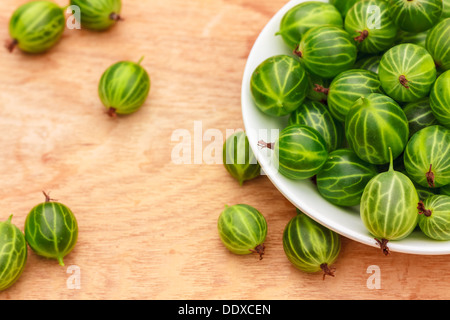 Piatto bianco riempito con piante succulente succosa fresche e mature Ribes verde su un vecchio tavolo di legno alto. Foto Stock