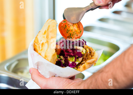 Döner Kebab - gentile venditore in un bagno turco di fast food eatery, con una fresca fatta pane pita o kebab Foto Stock