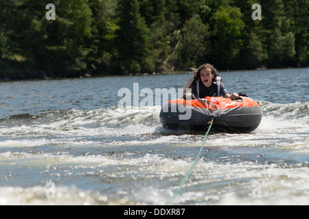 Ragazza godendo su una zattera gonfiabile, il lago dei boschi, Keewatin, Ontario, Canada Foto Stock