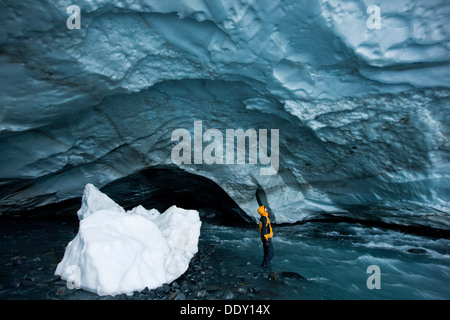 Alpinista guardando il soffitto di una caverna di ghiaccio, flusso glaciale che fluisce attraverso una caverna di ghiaccio del ghiacciaio Matanuska Foto Stock