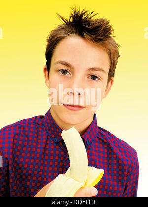 Ritratto, boy, adolescente di mangiare una banana Foto Stock