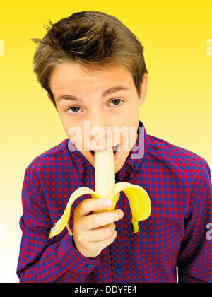 Ritratto, boy, adolescente di mordere una banana Foto Stock