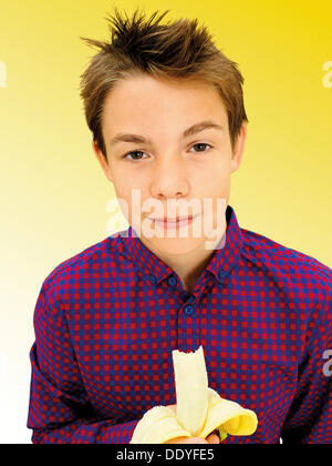 Ritratto, boy, adolescente di mangiare una banana Foto Stock