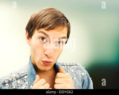 Giovane con un viso stupito indossando un chiodati camicia denim, ritratto Foto Stock