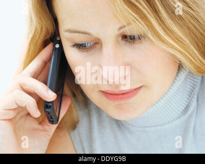 Ritratto di una giovane donna con un viso grave, concentrato, telefono cellulare Foto Stock