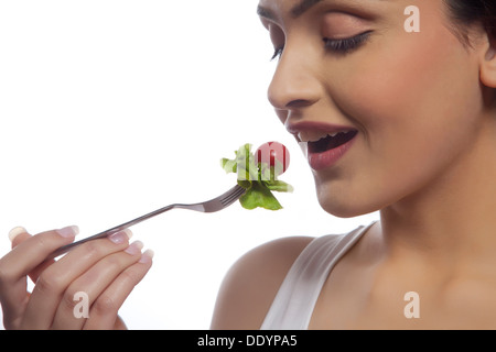 Close-up di giovane donna mangiare insalata contro uno sfondo bianco Foto Stock