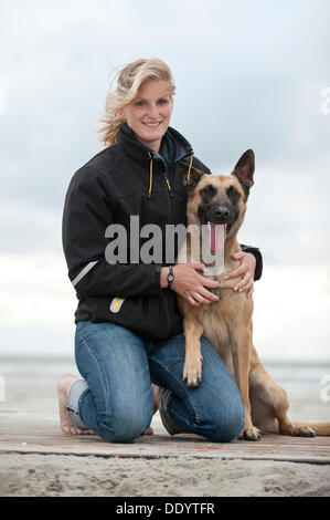 Donna con un Hollandse Herdershond, olandese pastore, seduto su una spiaggia, Sankt Peter-Ording, Schleswig-Holstein Foto Stock