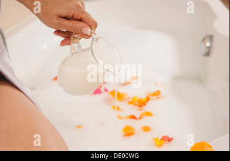 Donna versando il latte in una vasca da bagno Foto Stock