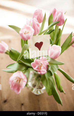 I tulipani in vaso, carta nota con un cuore Foto Stock