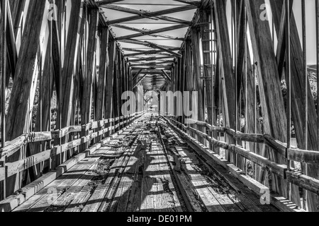 Drammatico, in legno antico ponte ferroviario attraversamento Red Deer river, è stata utilizzata per spostare il carbone. Decadimento e abbandonate e arrugginite rotaie. B&W HDR Foto Stock