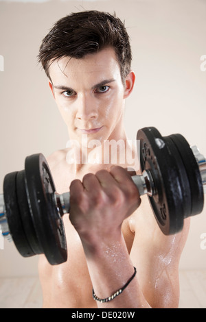 Giovane uomo facendo il peso della formazione con manubri Foto Stock