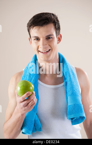 Sorridente giovane dopo fare sport in possesso di un Apple nella sua mano Foto Stock