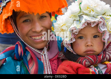 La donna e la sua figlia indossando il tradizionale cofani andina, Pisac Market, la Valle Sacra degli Incas, vicino a Cusco, Perù Foto Stock