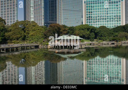 Nakajima Tea House tra le riflessioni di Shiodome skyline nel laghetto Shioiri, Hama Rikyu Teien (Hamarikyu giardino separato), Tokyo, Giappone Foto Stock