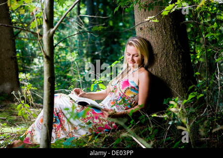 Giovane donna nella foresta, lettura Foto Stock