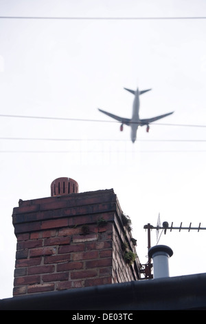 Aeroplano volando a bassa quota sopra la casa superiore del tetto. Foto Stock