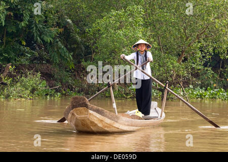 Donna vietnamita canottaggio attraverso un affluente del fiume Mekong, Delta del Mekong, Vietnam, sud-est asiatico Foto Stock