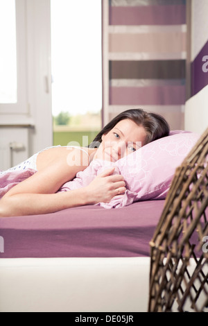 Giovane donna giaceva a letto in una camera da letto Foto Stock