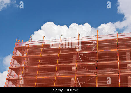 Ponteggio con orange una rete di protezione su un alto sito in costruzione Foto Stock